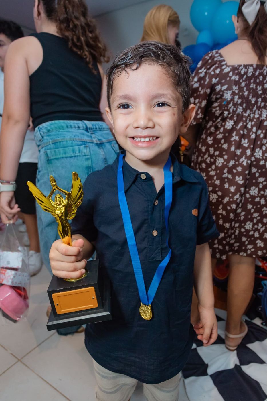 Criança sorrindo com troféu e medalha